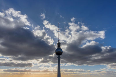 Low angle view of communications tower against cloudy sky