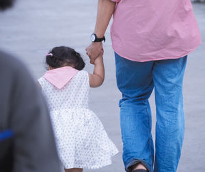 Rear view of father and daughter walking on road