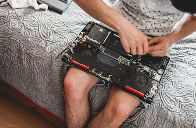 A young man is changing the thermal paste on a laptop.