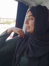 Woman wearing hijab while looking away in car