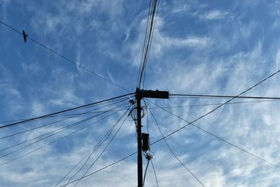 Low angle view of electricity pylon against cloudy sky
