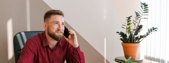 Happy businessman at his desk in office talking on phone. a young businessman