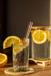 Glass of water with fresh lemon juice with reusable glass straws detox cold tonic water with sunny