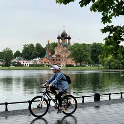 Man riding bicycle by river against sky