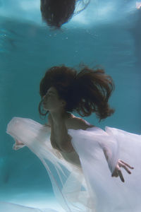Woman with curtain swimming in pool
