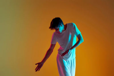 Side view of woman standing against yellow background