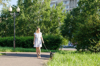 Full length of woman on street against trees