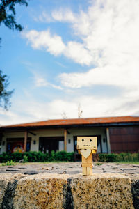 Close-up of wooden figurine on floor against cloudy sky