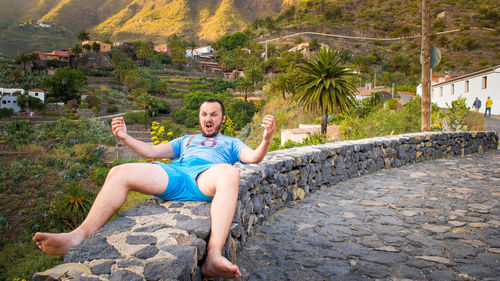 Mid adult man screaming while lying on rock against mountain