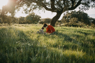 Mother and son crouching on grass at field