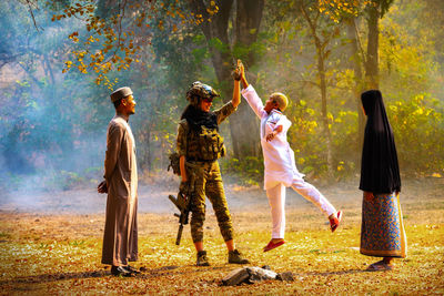 Boy giving high five to soldier at forest