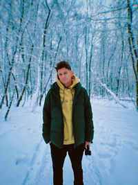 Young handsome stylish guy stands in a snow-white snowy forest, filmed