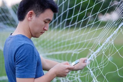 Man using phone while holding soccer net