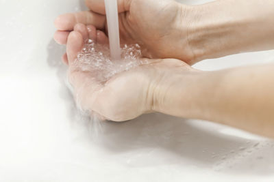 Close-up of woman holding hands over white background