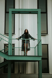 Full length portrait of young woman standing outside building