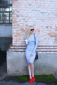 Beautiful woman standing by wall