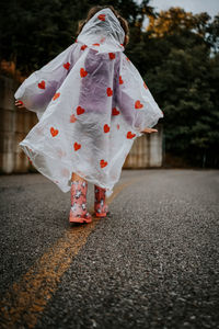 Low section of person with umbrella walking on road