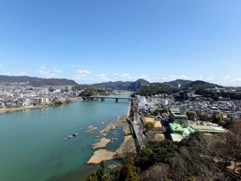 High angle view of townscape by river against blue sky