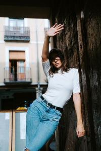 Portrait of young woman standing against tree