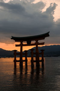 Silhouette floating torii gates against sky during sunset