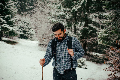 Young man standing on snow covered forest