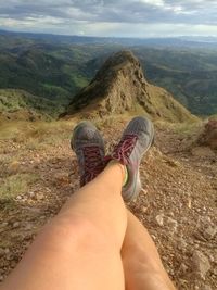 Low section of woman standing on mountain against sky