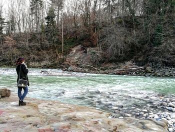 Full length of man standing by river in forest