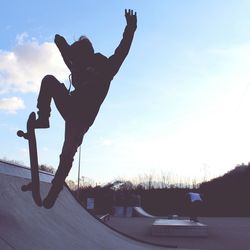 Silhouette man skateboarding on skateboard against sky