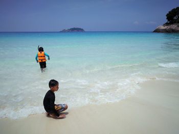 Boys on beach against sky