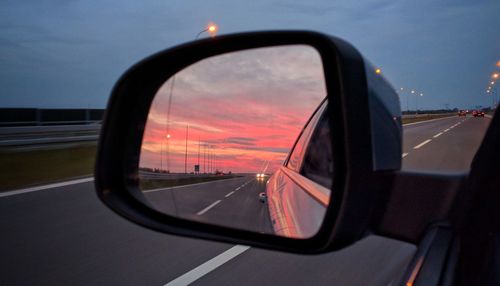 Reflection of sky on side-view mirror at sunset