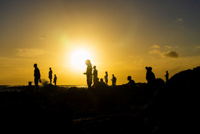 Silhouette of people on top of the beach rocks. late afternoon in salvador, bahia, brazil.