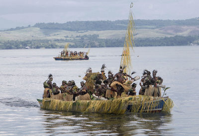 Tribal people in lake sentani against mountain