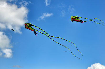 Low angle view of kites flying against blue sky