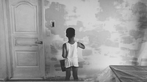 Rear view of boy painting wall at home