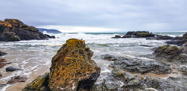 Rock formations on shore against sky