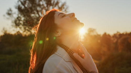 Beautiful girl in the countryside in front of the setting sun