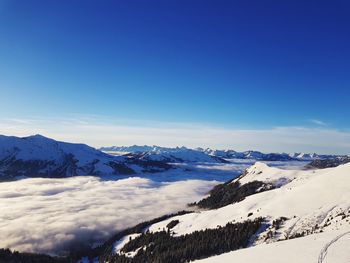 Scenic view of snowcapped mountains against blue sky