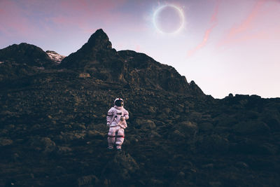 Rear view of man standing on rock against sky