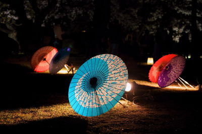 Illuminated japanese unbrela on field at night