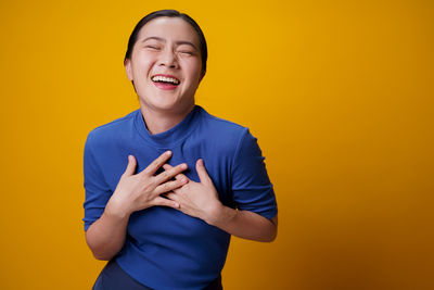 Full length of man standing against yellow background