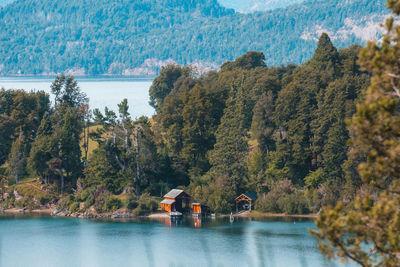 People on lake by trees against mountain
