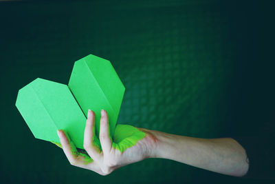 Cropped hand holding green heart shape paper