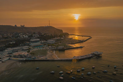 High angle view of cityscape by sea against sky during sunset