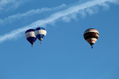 Low angle view of hot air balloons flying against blue sky