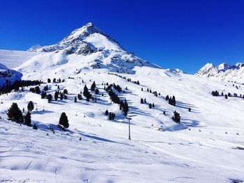 Panoramic view of snow covered landscape against clear blue sky