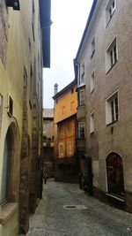 Narrow alley amidst buildings in city against sky