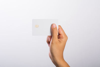 Close-up of woman hand holding blank credit card against white background