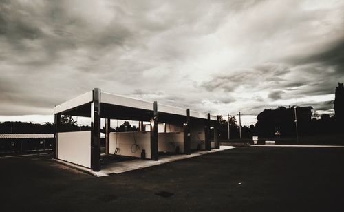 Road amidst buildings against dramatic sky