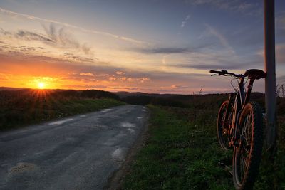 Bicycle on road against sky during sunset