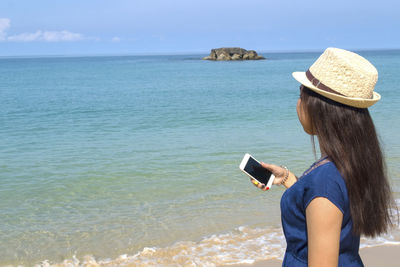 Rear view of woman on beach against sky